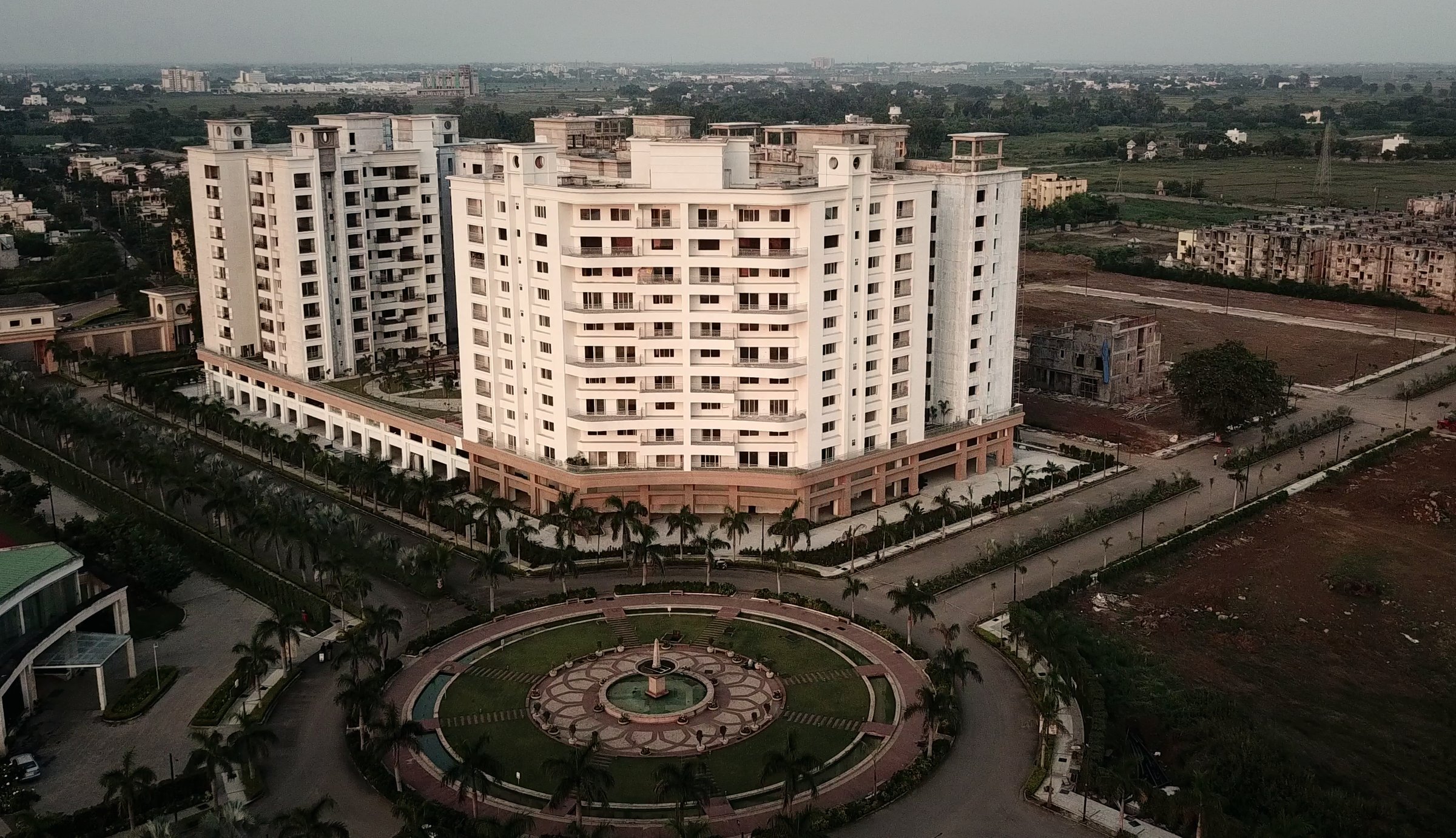 Anandam World City at dusk — the fountain roundabout and residential towers